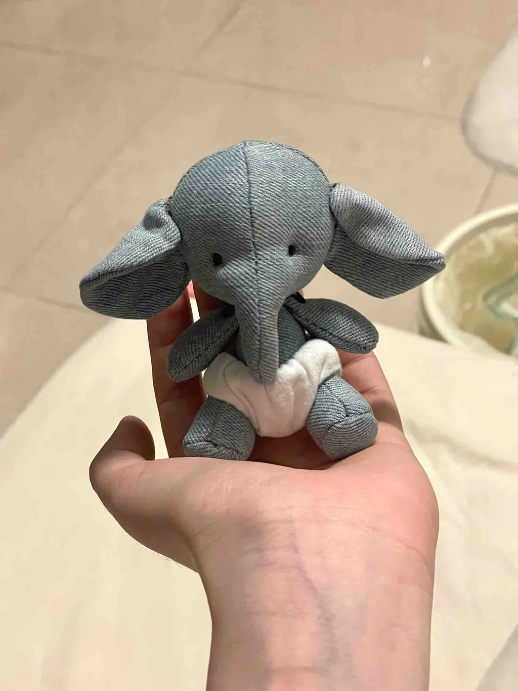 Small handmade grey elephant plush sitting in a person's palm