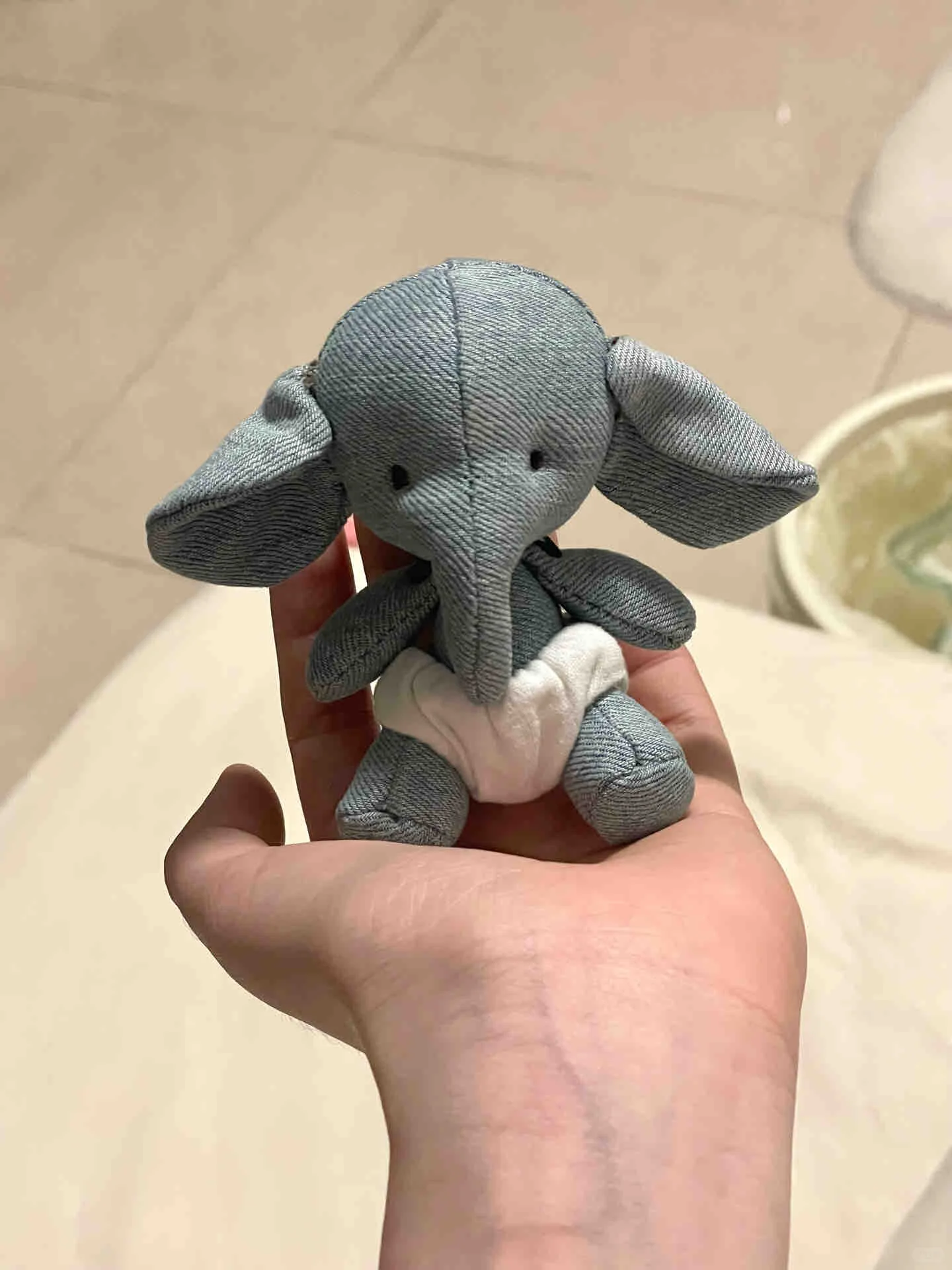 Small handmade grey elephant plush sitting in a person's palm