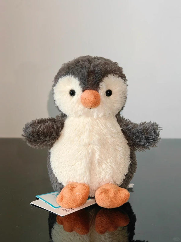 Plush penguin toy with a tag on a reflective surface