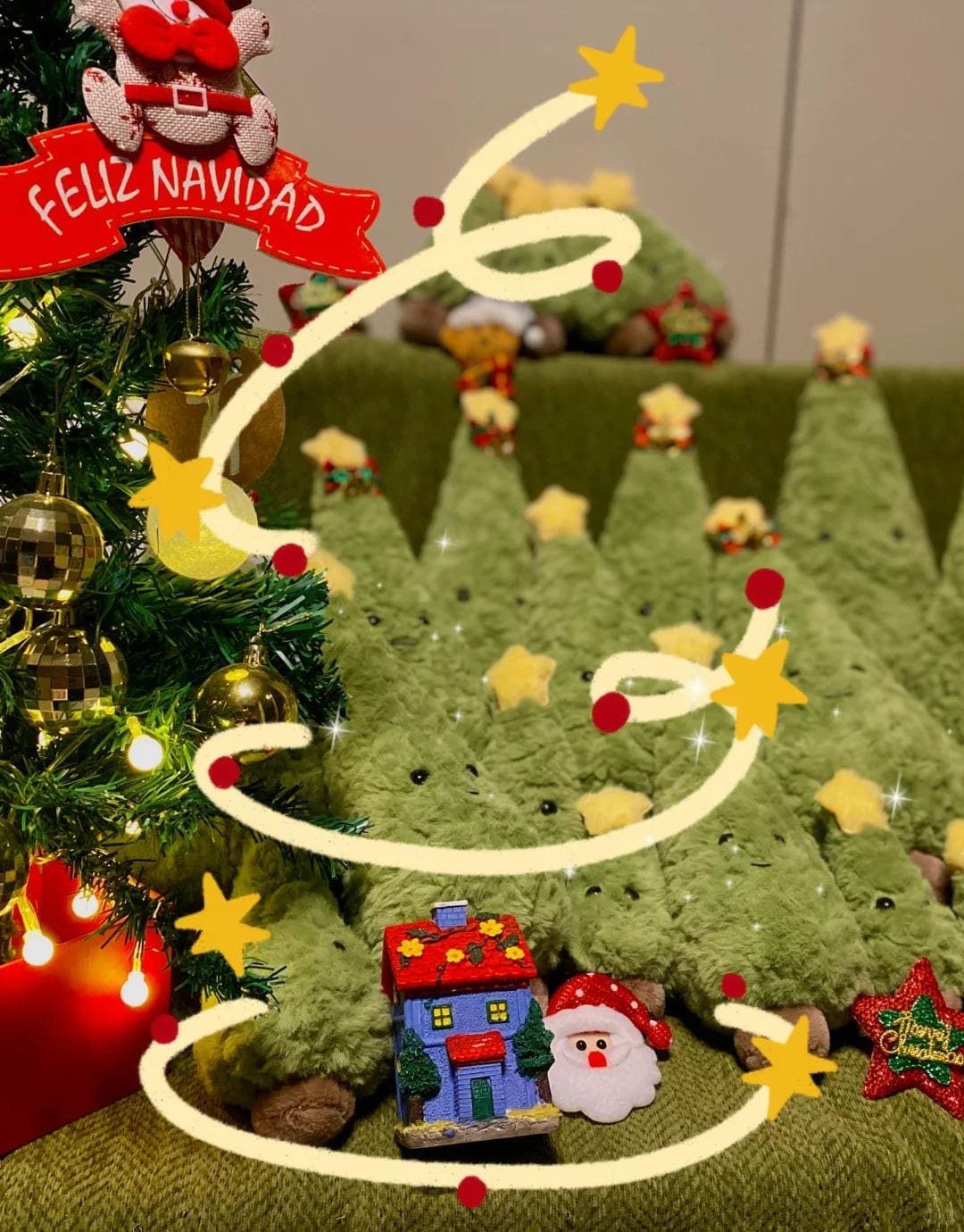 Decorated Christmas tree with plush trees, lights, and festive decorations on a green surface.