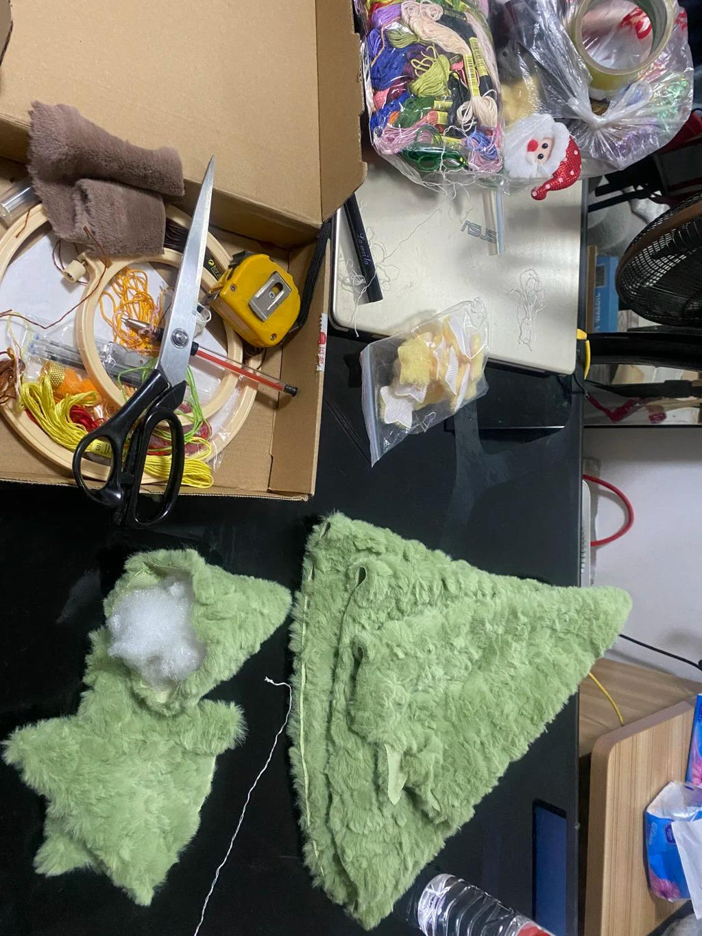 Green felt star and triangle shapes on a black surface with various items in the background.