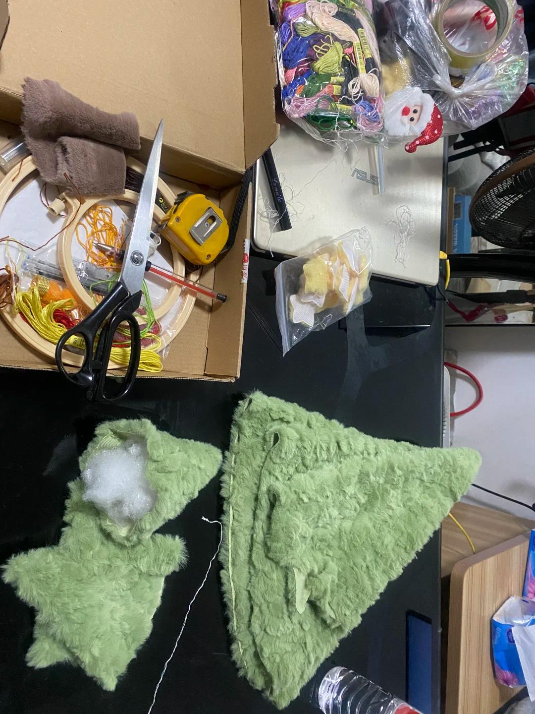 Green felt star and triangle shapes on a black surface with various items in the background.