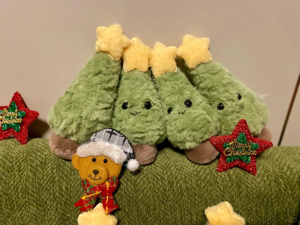 Three green plush Christmas trees with yellow stars on a green surface, surrounded by festive decorations.