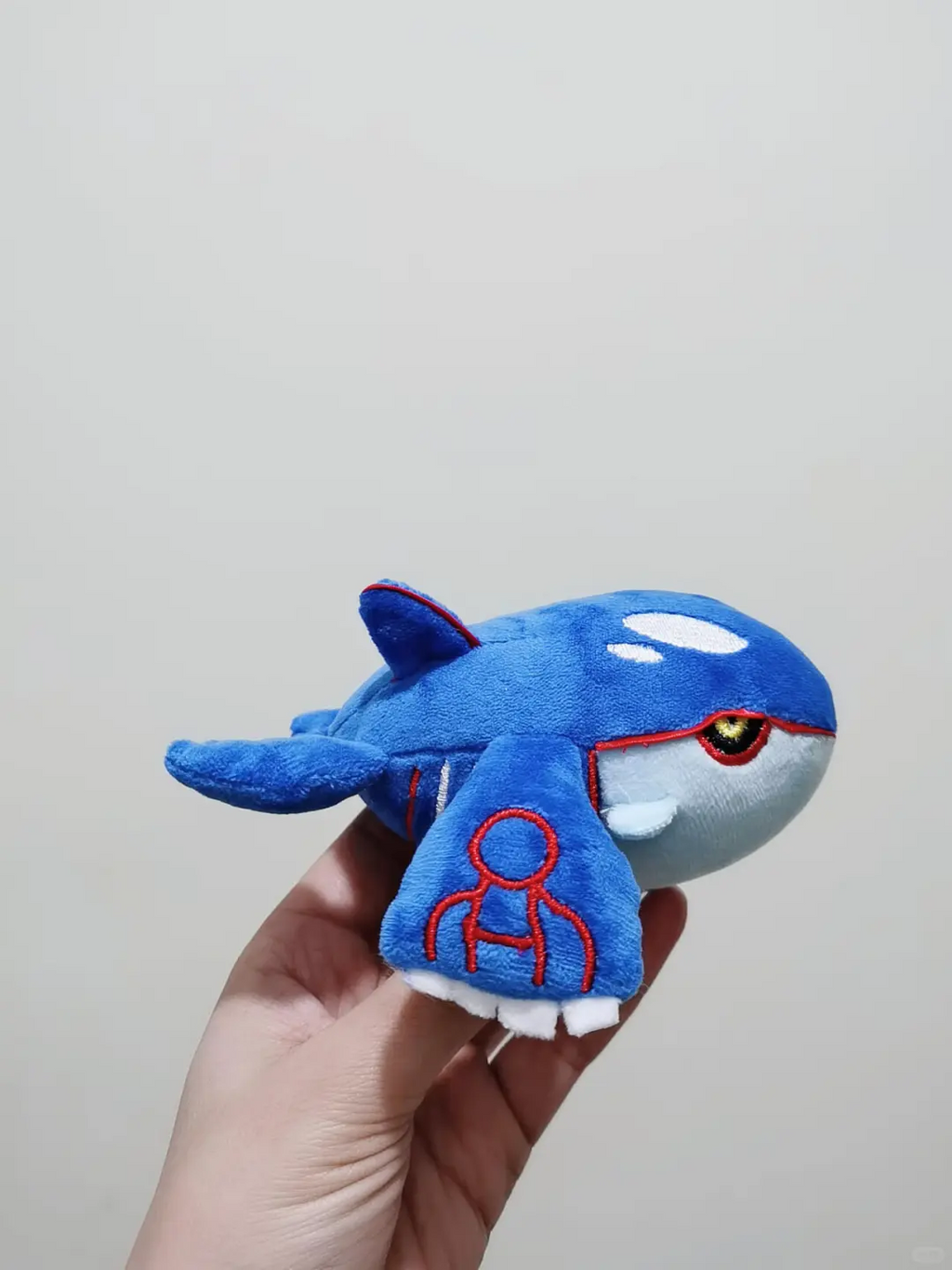 Handmade blue Kyogre plush showing the face, fins and red embroidered markings
