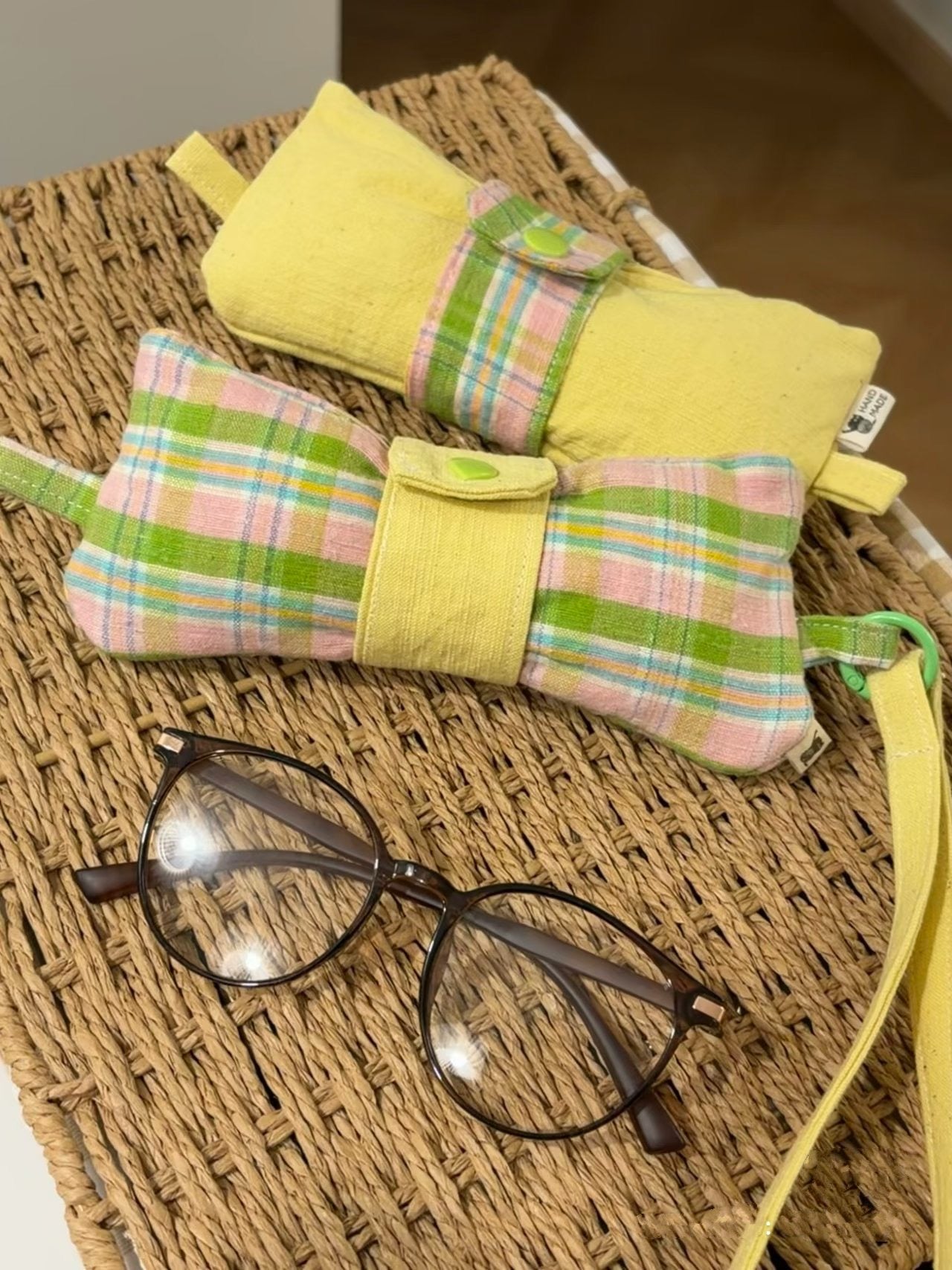Yellow and plaid glasses cases on a textured surface with glasses in front