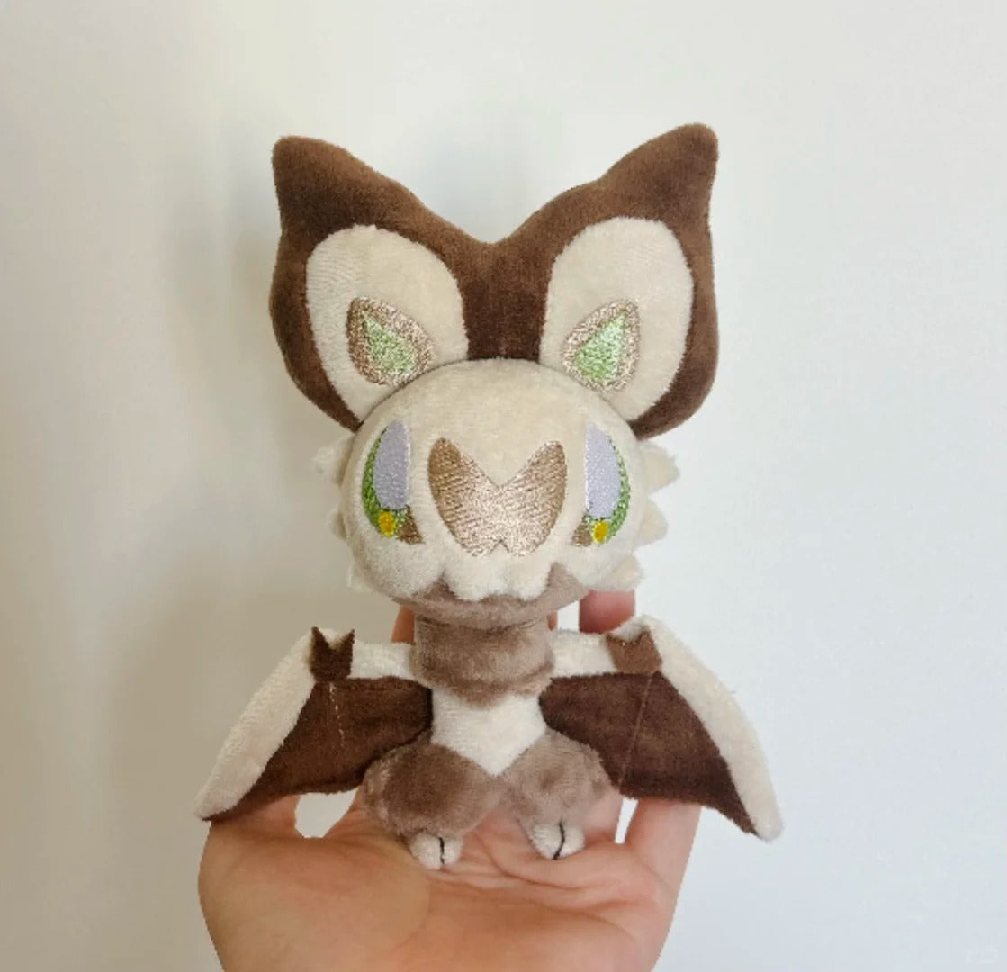 Front view of a handmade brown and cream Noibat plush with embroidered facial details and spread wings
