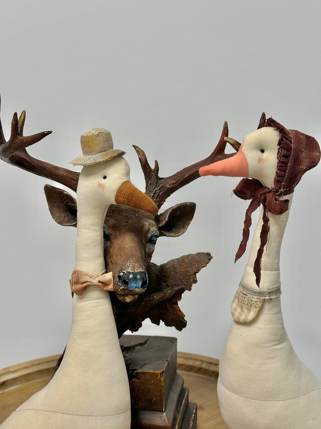 Two finished handmade fabric geese with hats and scarves