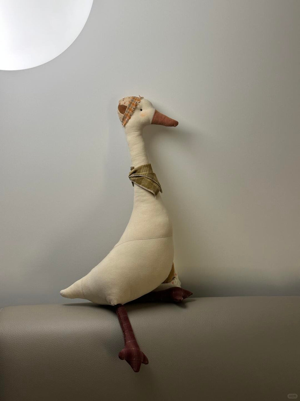Finished cream stuffed goose with a long neck, brown beak and feet, checked hat and scarf