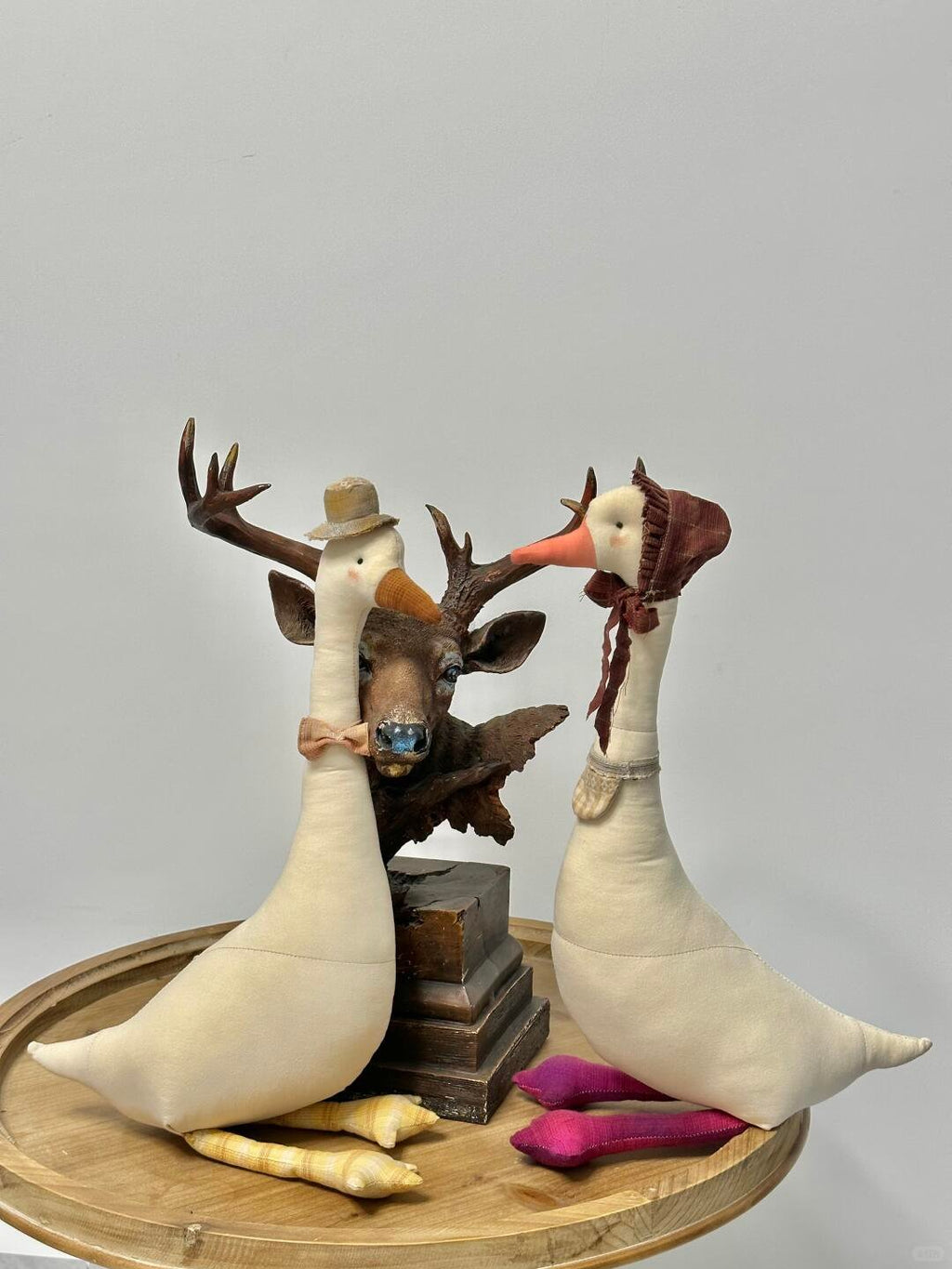 Two tall stuffed geese made from cream fabric with decorative accessories
