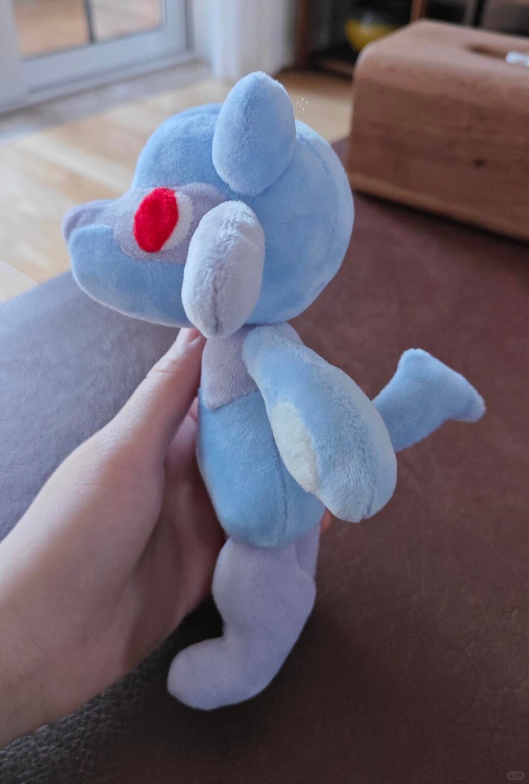 Side view of a light blue Lucario-inspired plush prototype showing the ear, arm patch and tail construction