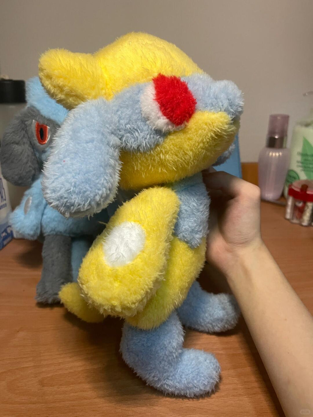 Large yellow and grey Lucario-inspired plush prototype held upright beside a blue colour variation