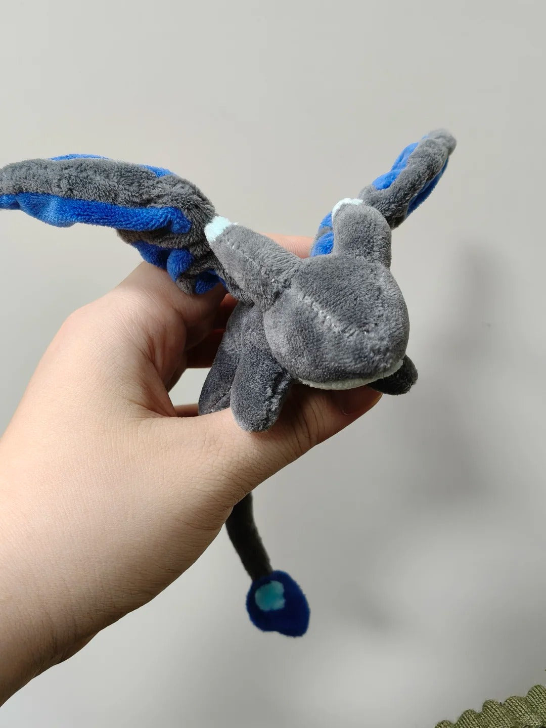 Palm-size grey and blue four-legged dragon plush held in one hand
