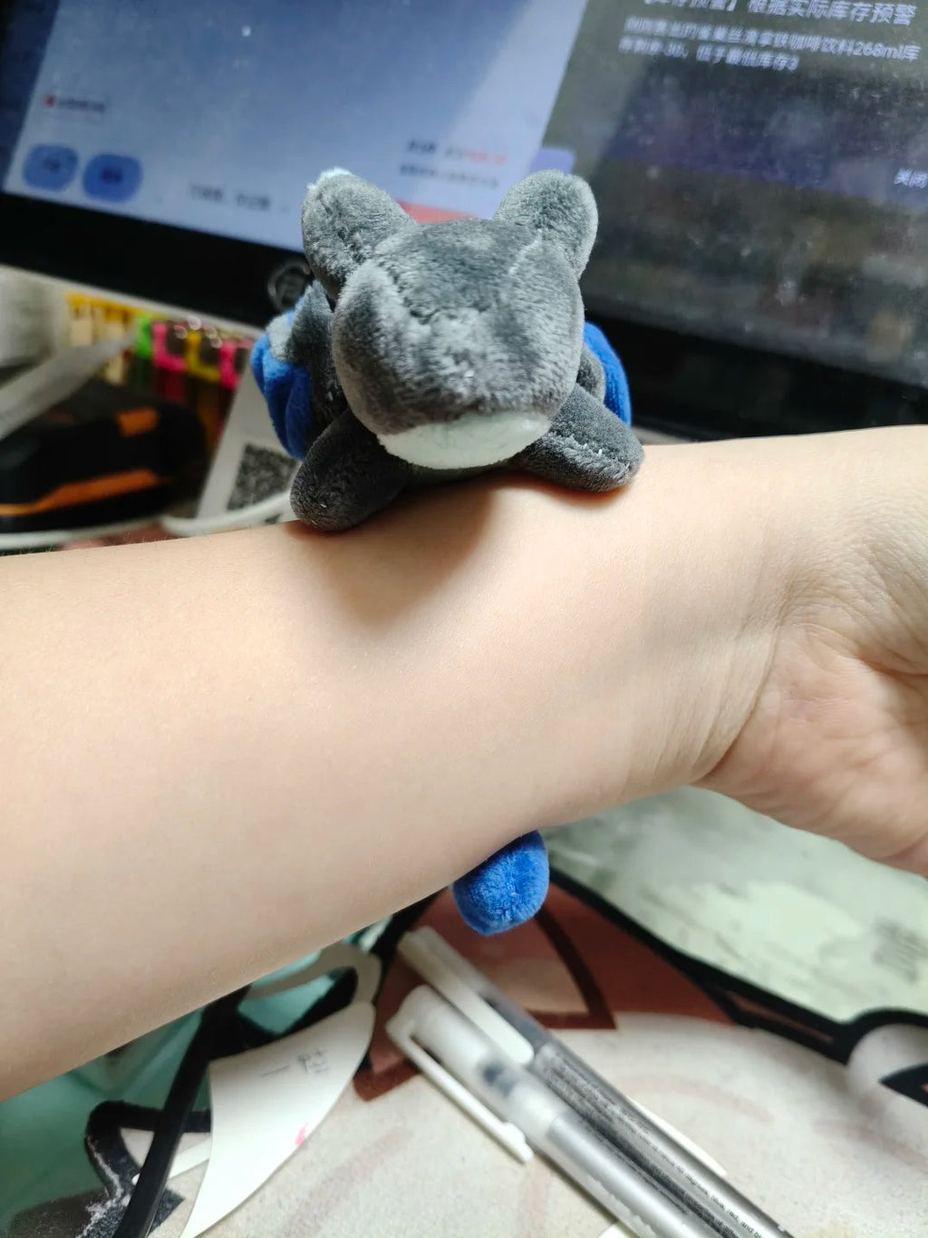 Mini grey dragon plush resting on a wrist to show its palm-size scale