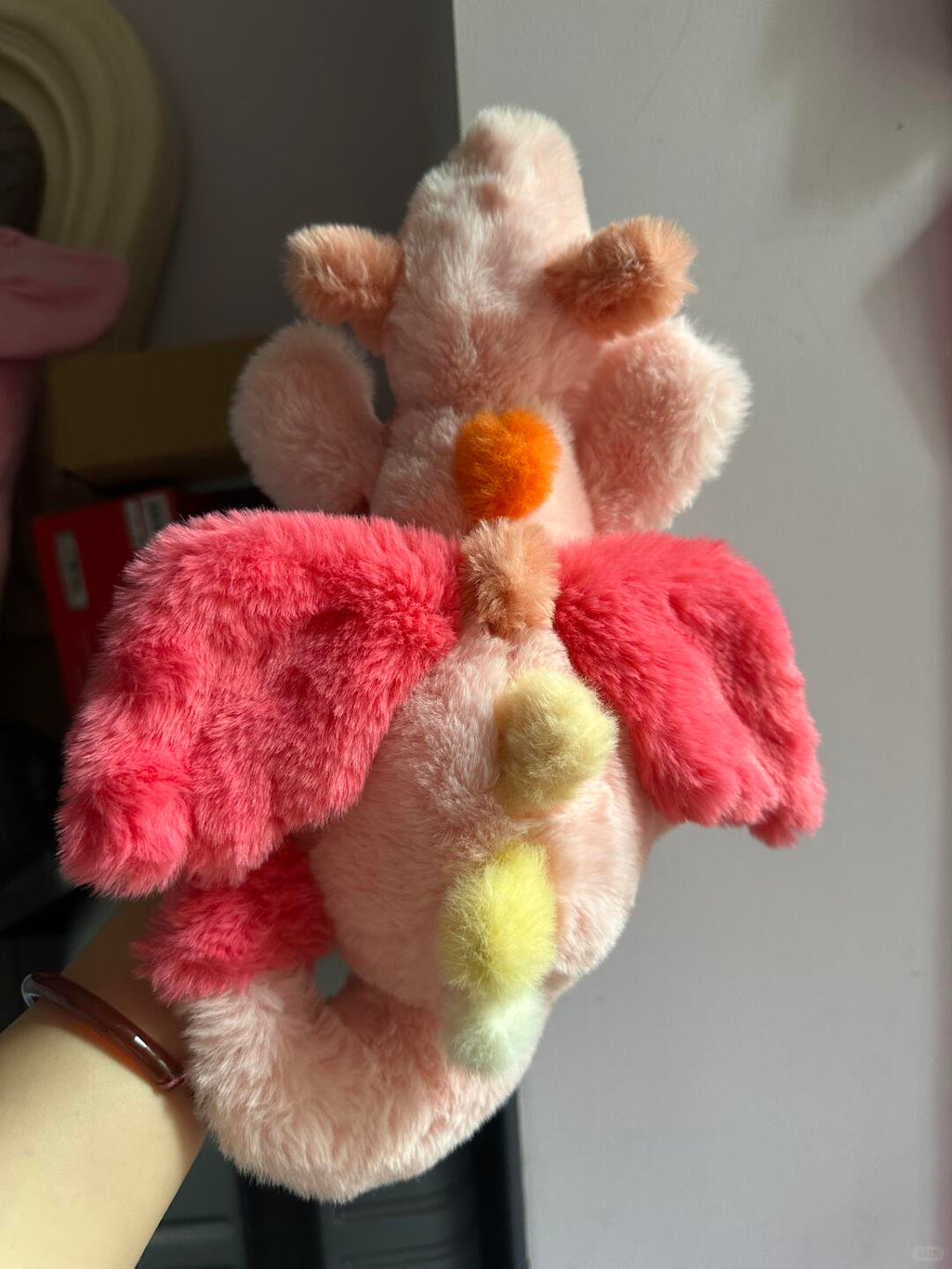 Back view of pink Sky Dragon plush sewing pattern sample with bright wings and pastel rainbow spines