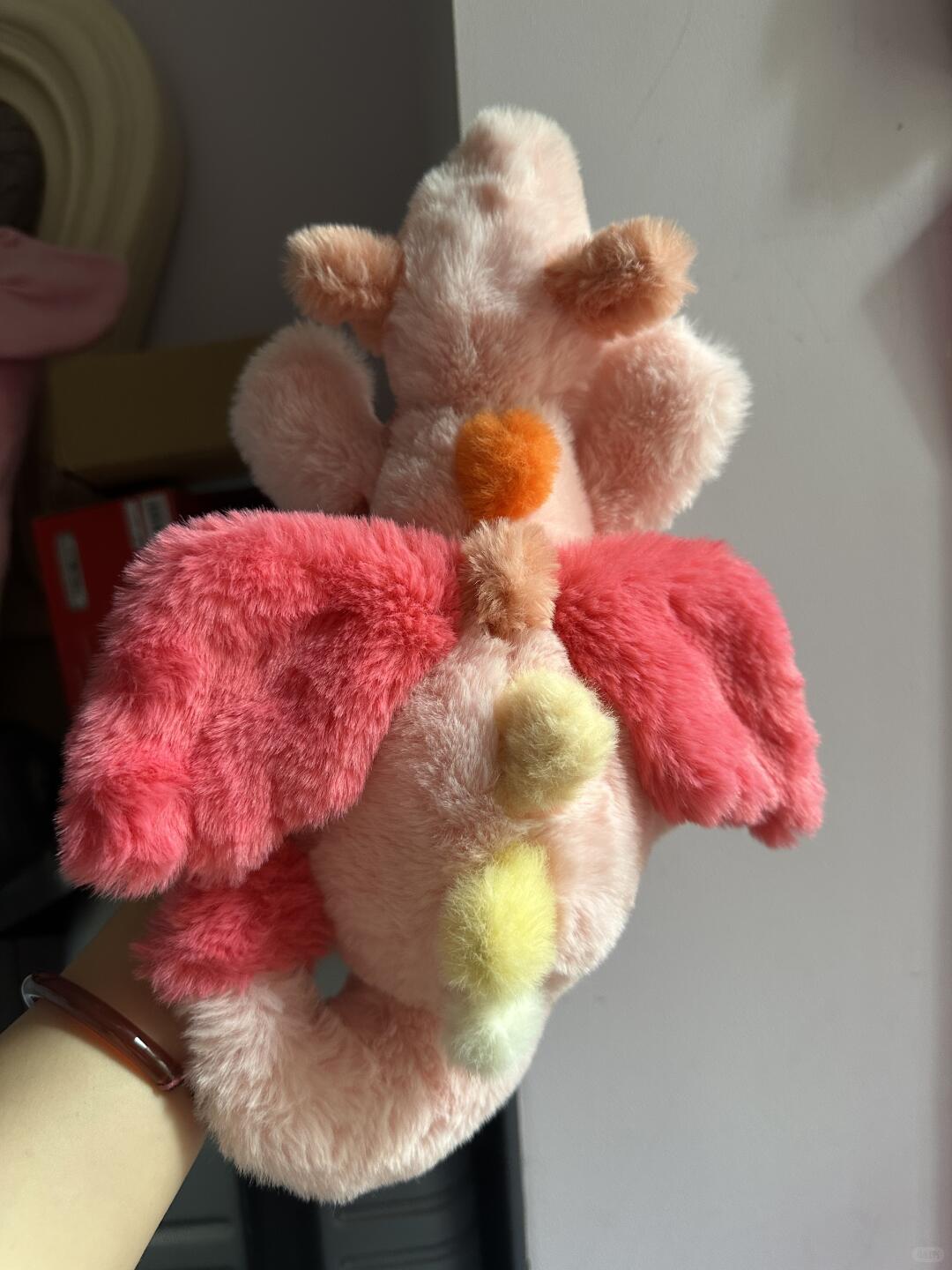 Back view of pink Sky Dragon plush sewing pattern sample with bright wings and pastel rainbow spines