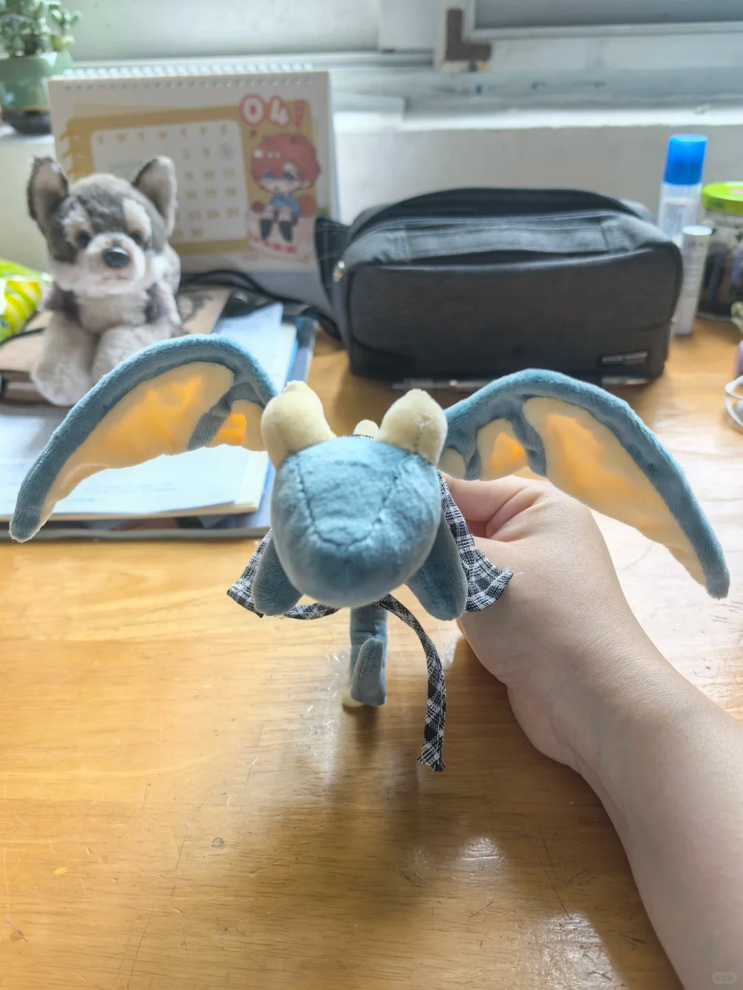 Front view of a posable blue dragon plush held up with both fabric wings spread