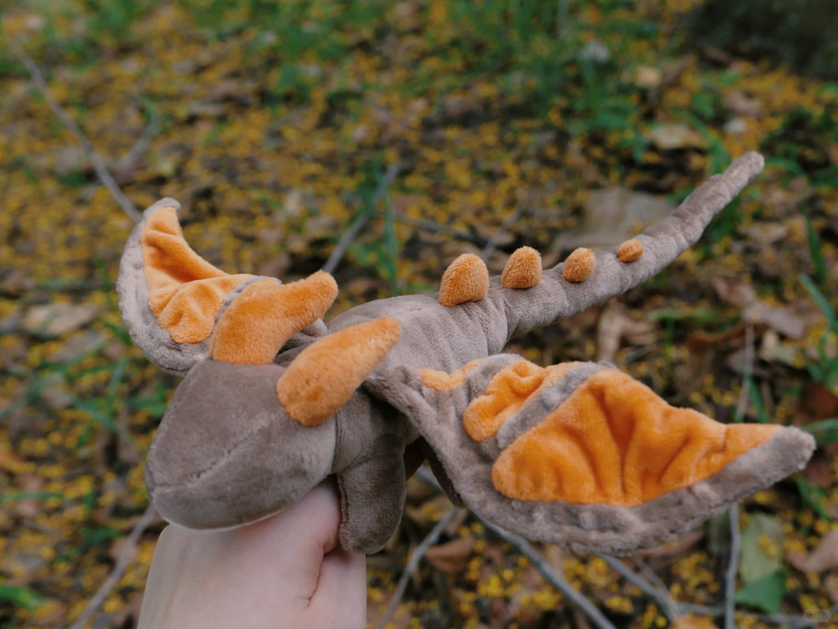 Grey and orange posable winged dragon plush with fabric wings and long tail outdoors