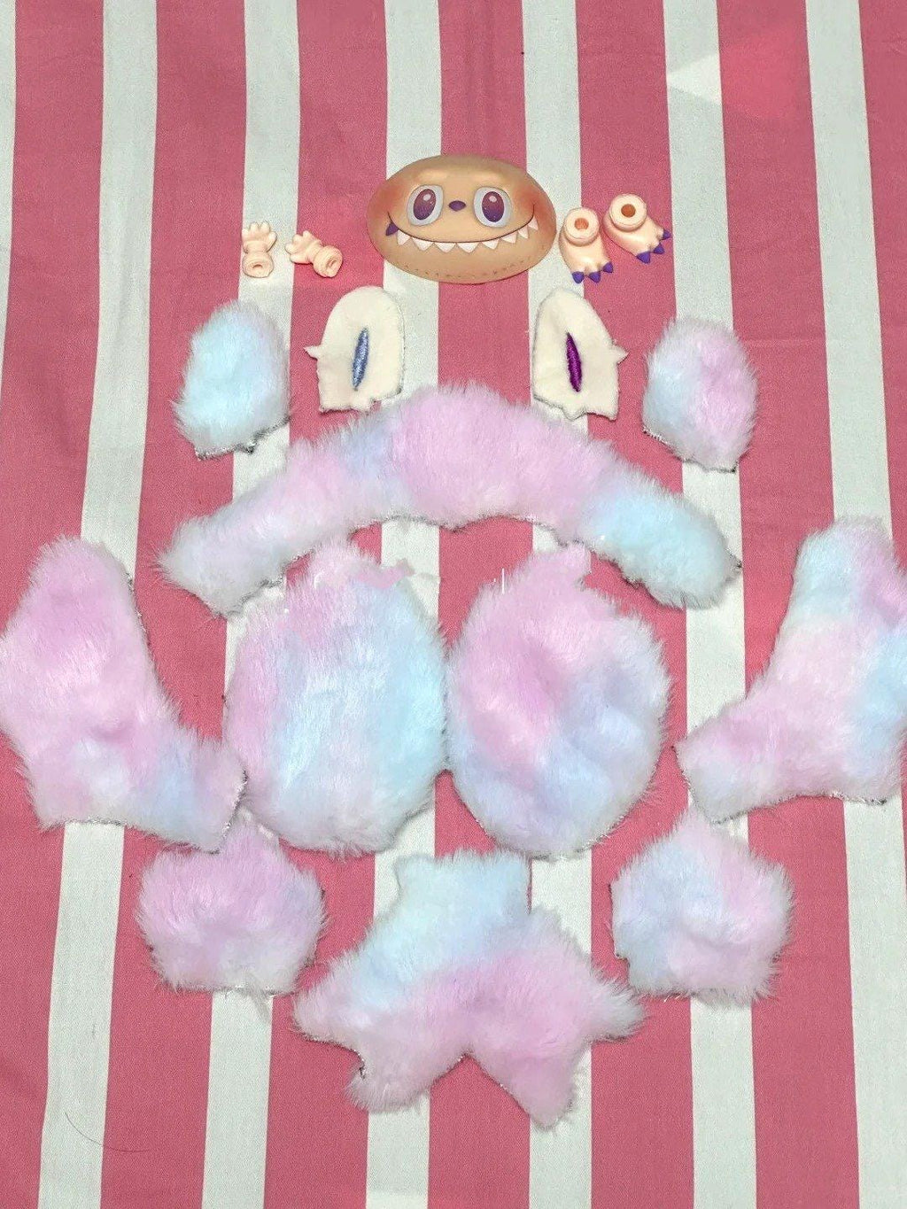 All materials and fabrics shape needed to make a labubu, labubu sewing pattern, Pink and white fluffy toy on a red and white striped background
