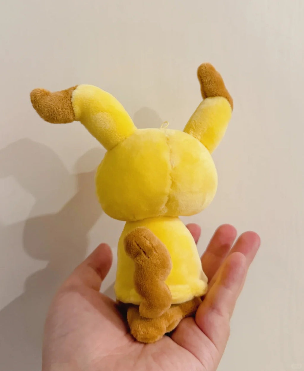 Back view of a handmade Mimikyu plush showing its brown zigzag tail