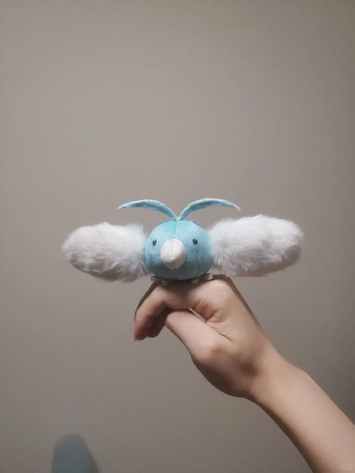 Blue Swablu plush balanced on a hand with fluffy cloud wings spread wide