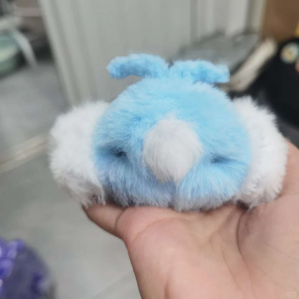 Fluffy blue Swablu plush displayed on an open palm