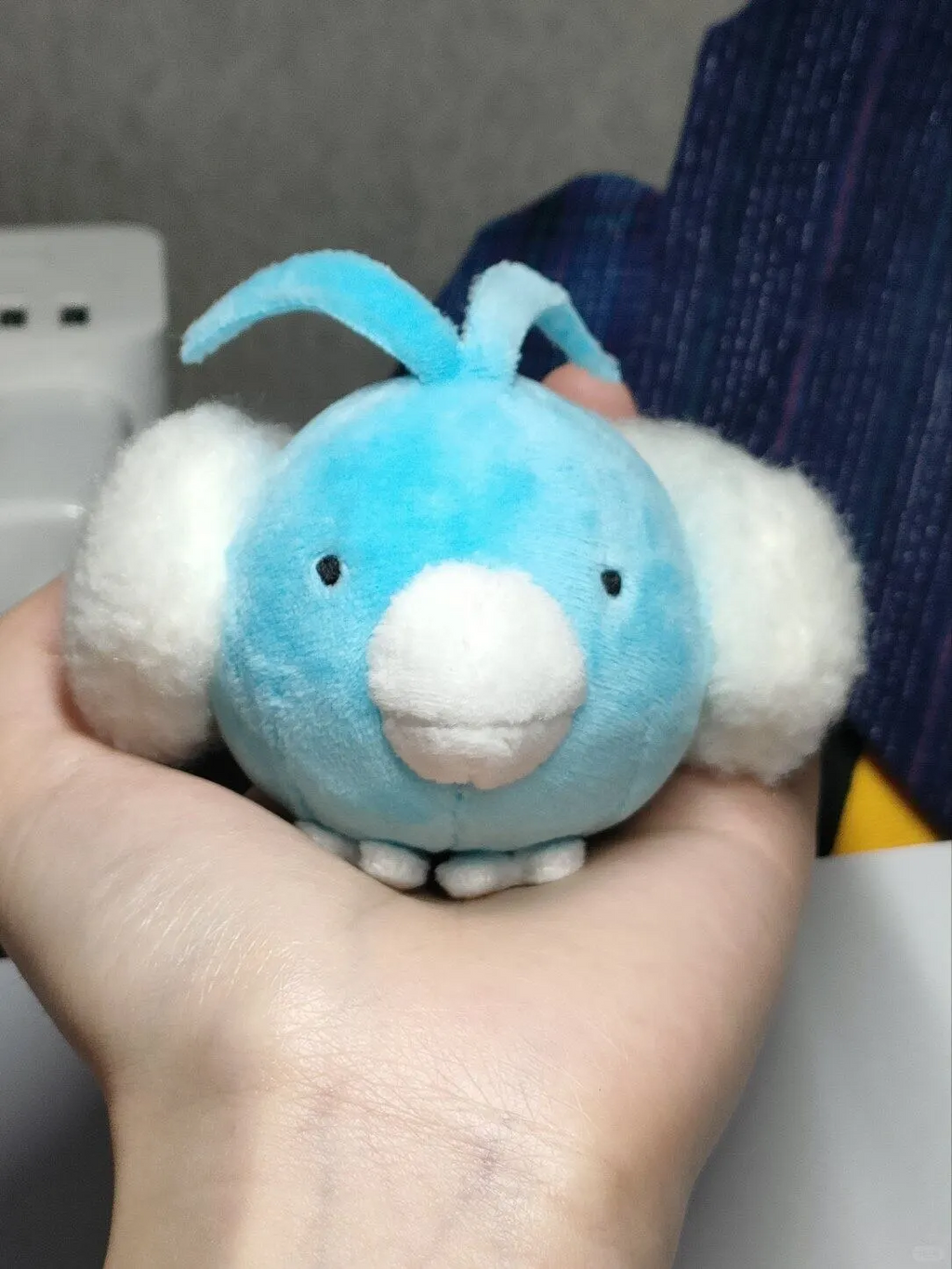 Front view of a small blue Swablu plush resting in one hand