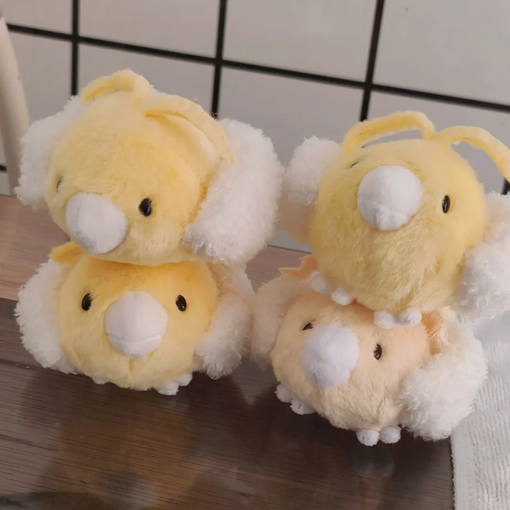 Four handmade yellow Swablu plush toys stacked together